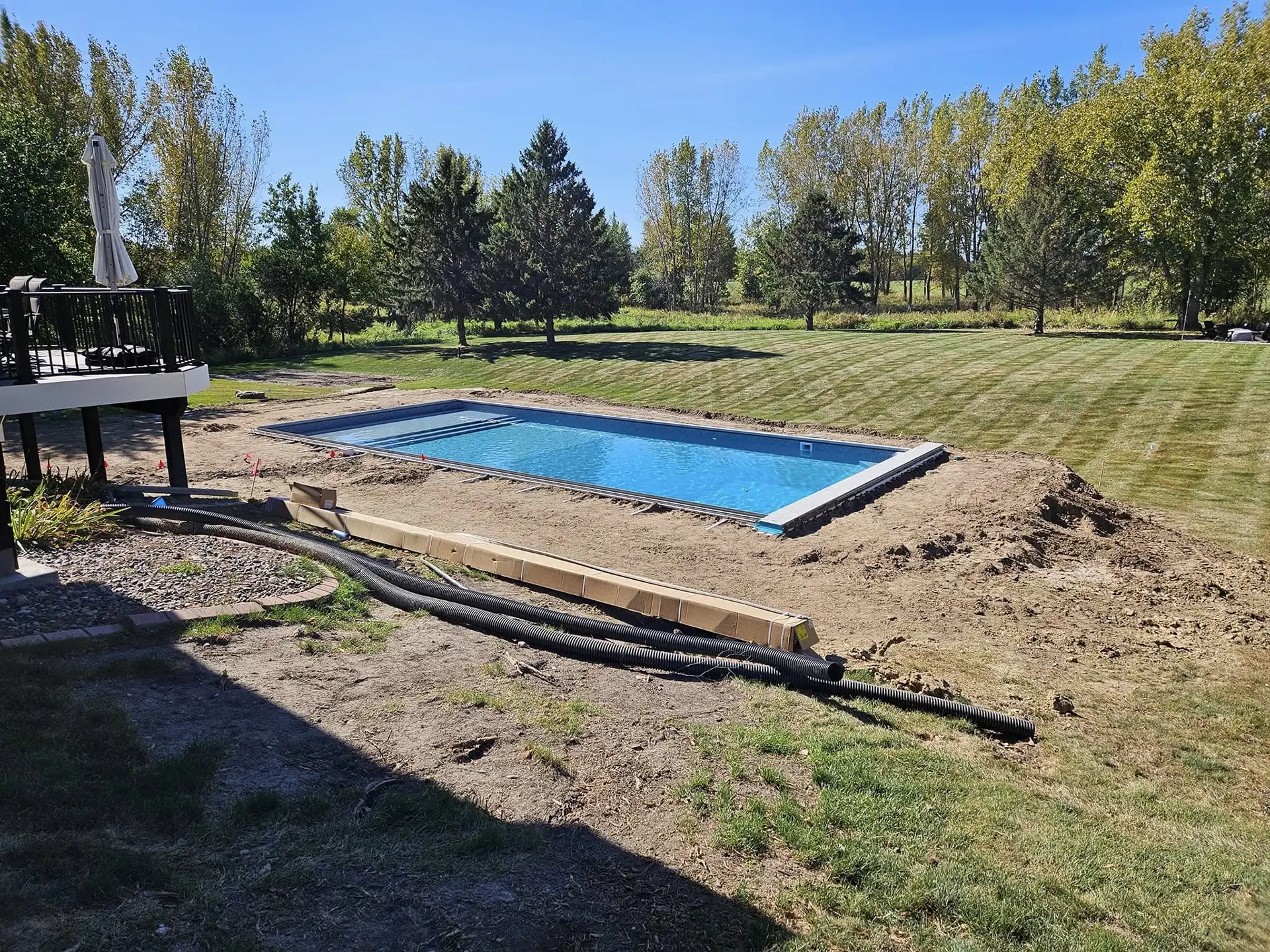 A backyard in White Bear Lake, MN, showing a partially completed swimming pool installation surrounded by fresh soil and landscaping preparations